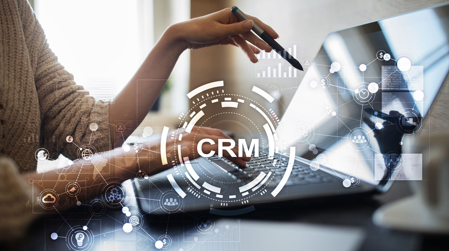 Gros plan sur un écran d'ordinateur affichant un tableau de bord CRM avec graphiques de ventes et liste de clients, clavier flouté en arrière-plan